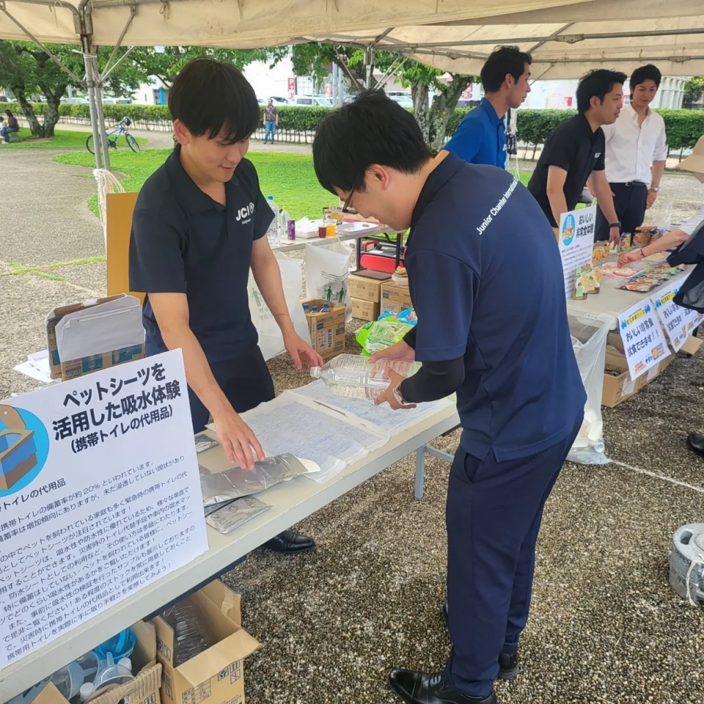 ペットシーツに水を注いで吸水性を確認し、緊急時の簡易トイレとしての有用性を検証、体験してもらっている様子